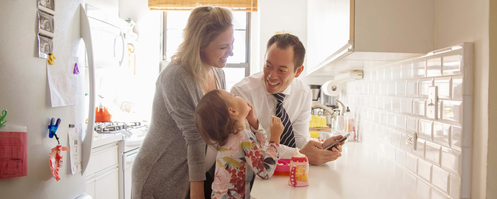 mother and father in kitchen with daughter eating breakfast