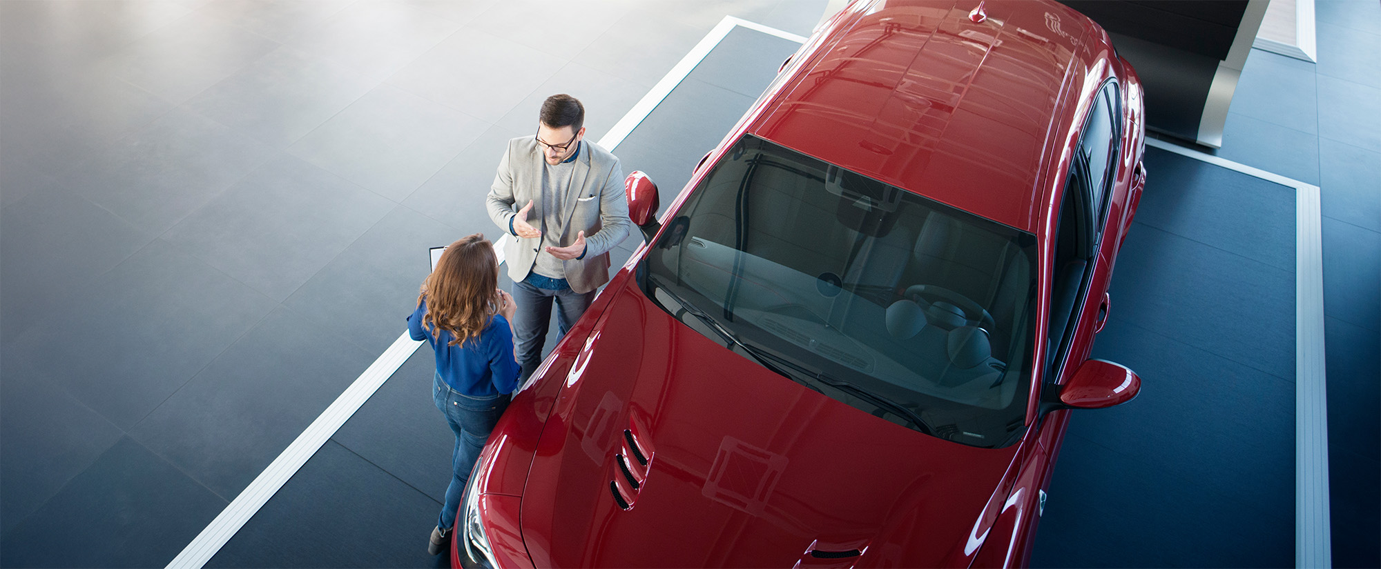 Top view of car salesperson and customer discussing terms of sale for new vehicle
