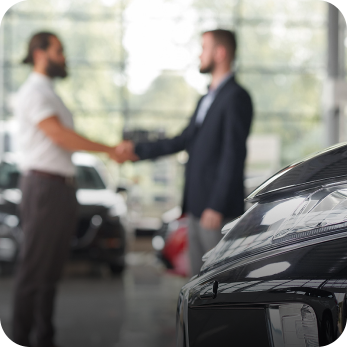 two people shakings hands in a car dealership