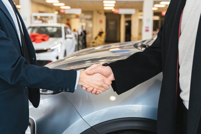 car dealer and person shaking hands
