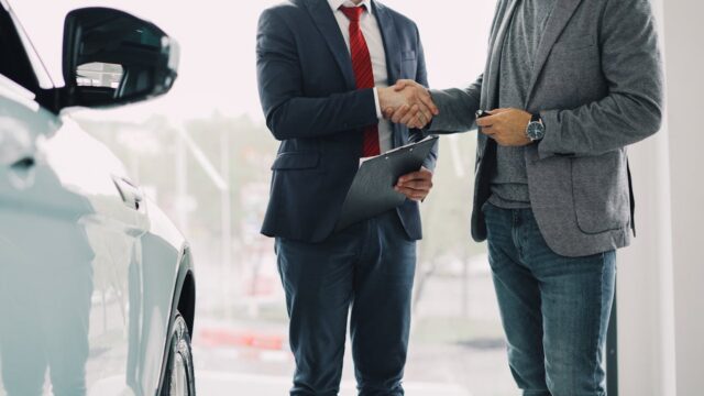 man shaking hands with car dealer